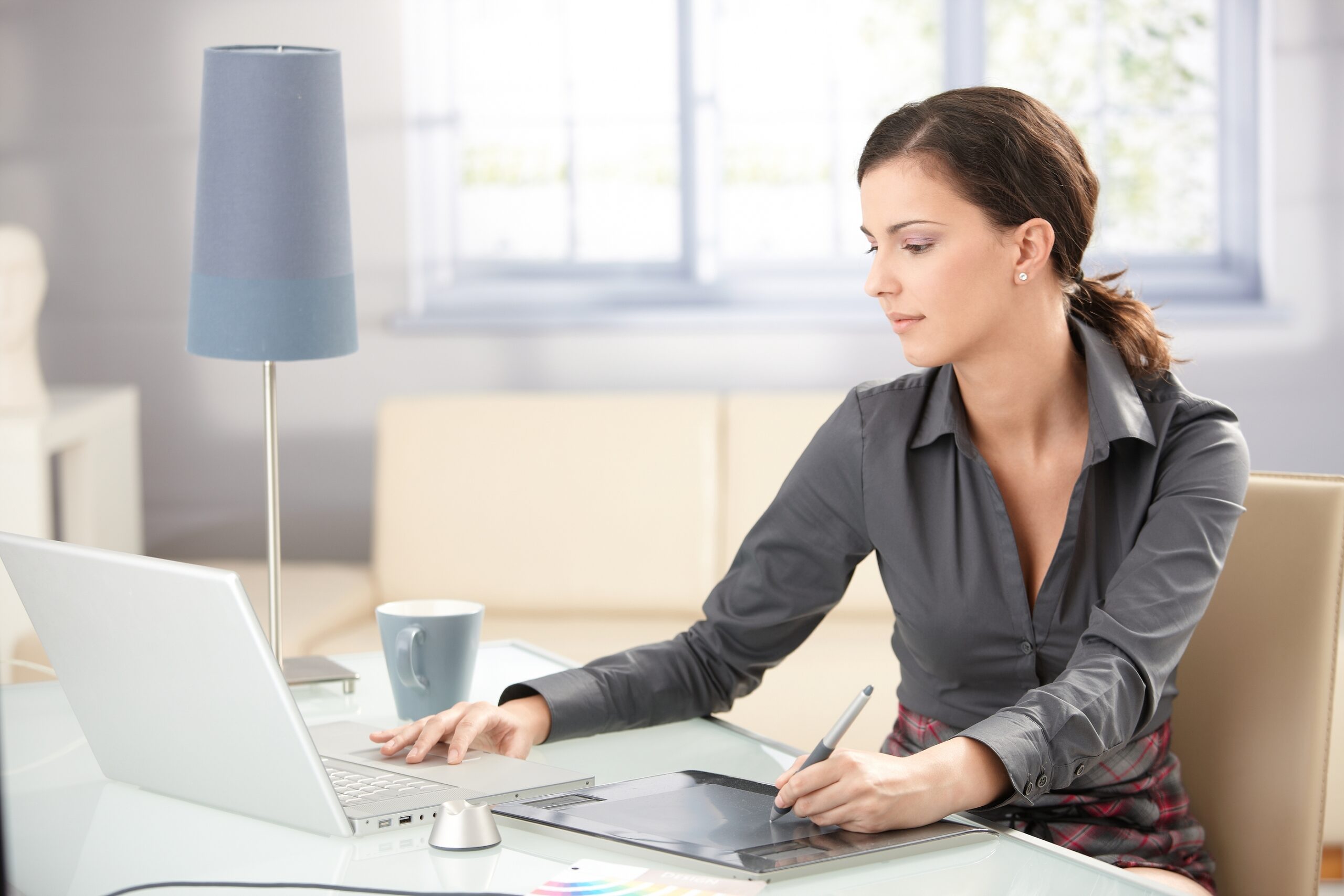 Young graphic designer working on laptop using tablet at home.?